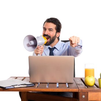 Businessman in his office shouting by megaphone